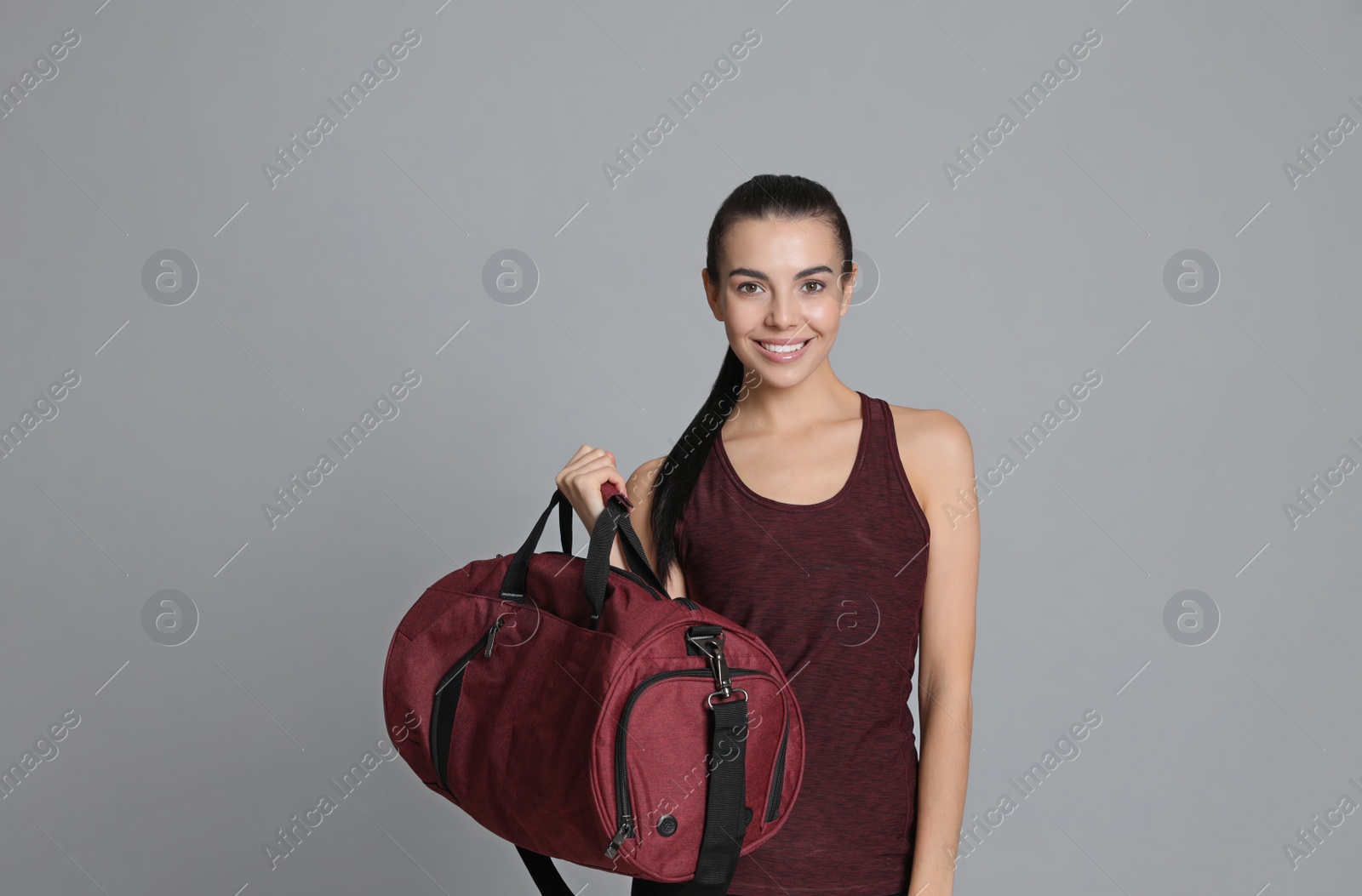 Photo of Beautiful woman with sports bag on grey background