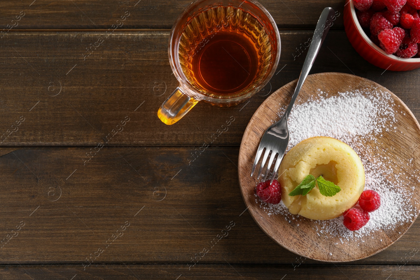 Photo of Tasty vanilla fondant with white chocolate and raspberries served on wooden table, flat lay. Space for text