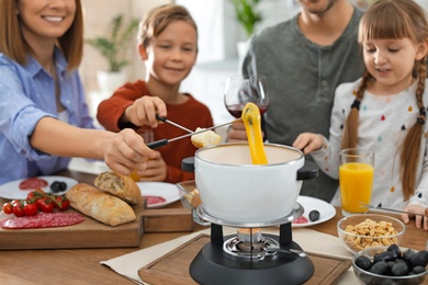 Happy family enjoying fondue dinner at home, selective focus