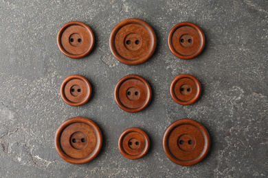 Brown sewing buttons on grey stone background, flat lay