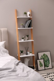 Photo of Stylish bedroom interior with decorative ladder and plants near grey wall
