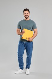 Happy man with folder on light gray background