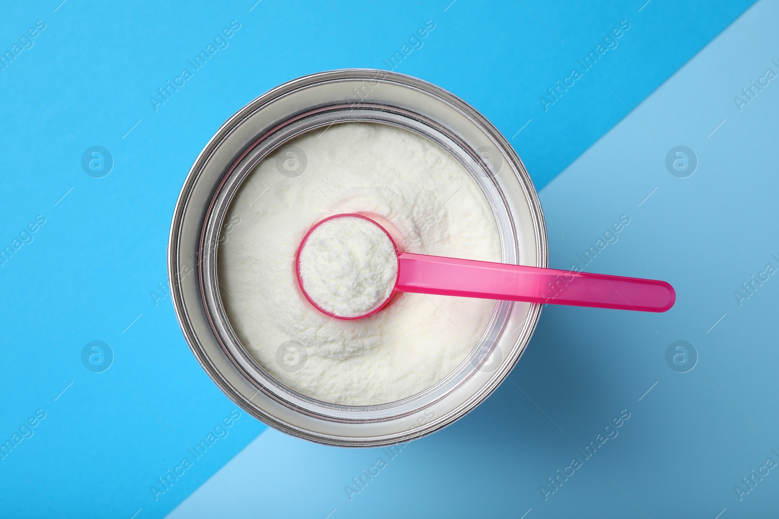 Photo of Can of powdered infant formula with scoop on color background, top view. Baby milk