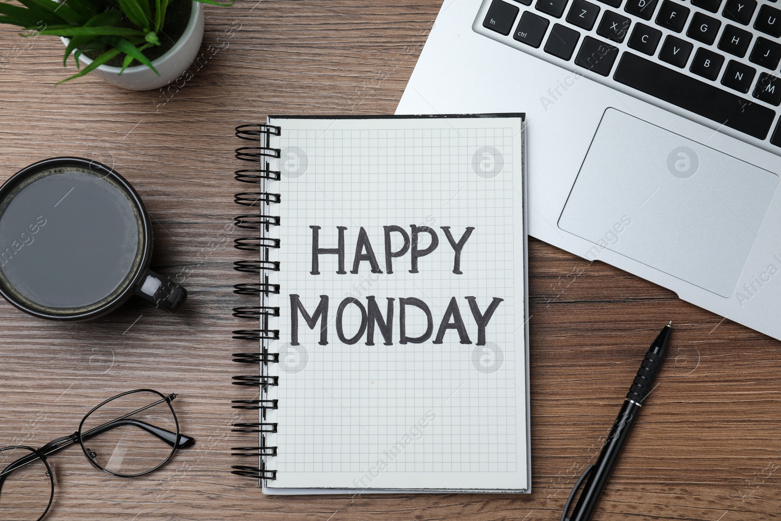 Photo of Message Happy Monday written in notebook, laptop and cup of coffee on wooden desk, flat lay