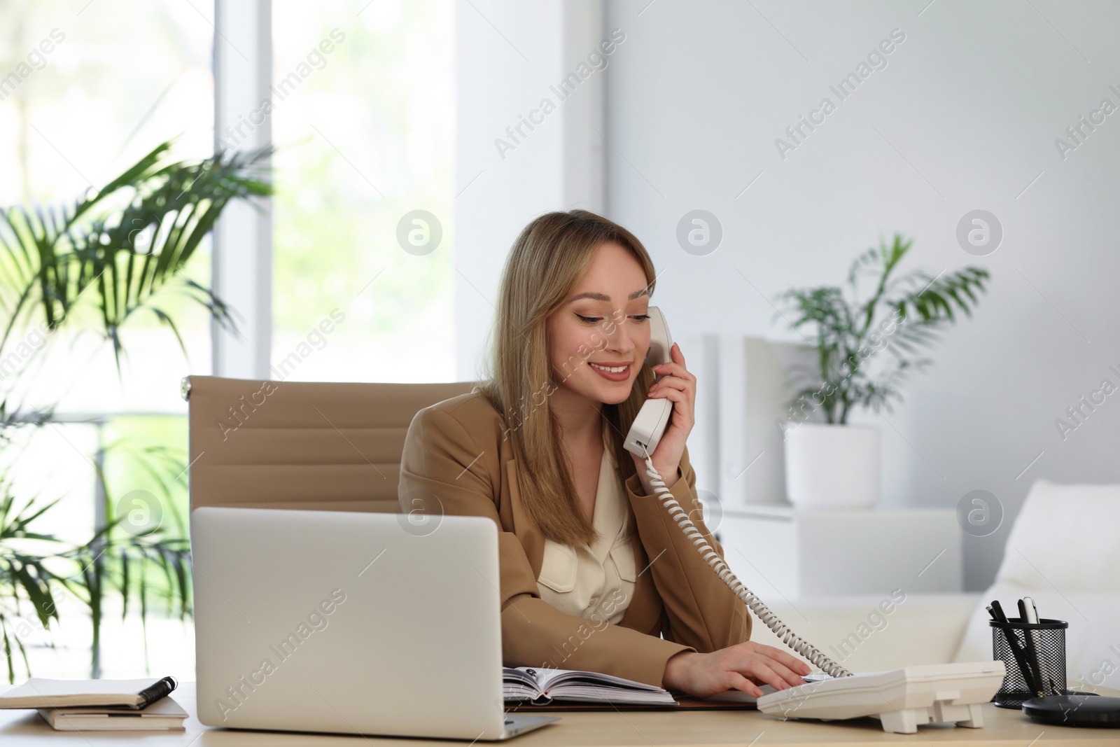 Photo of Secretary talking on phone at wooden table in office