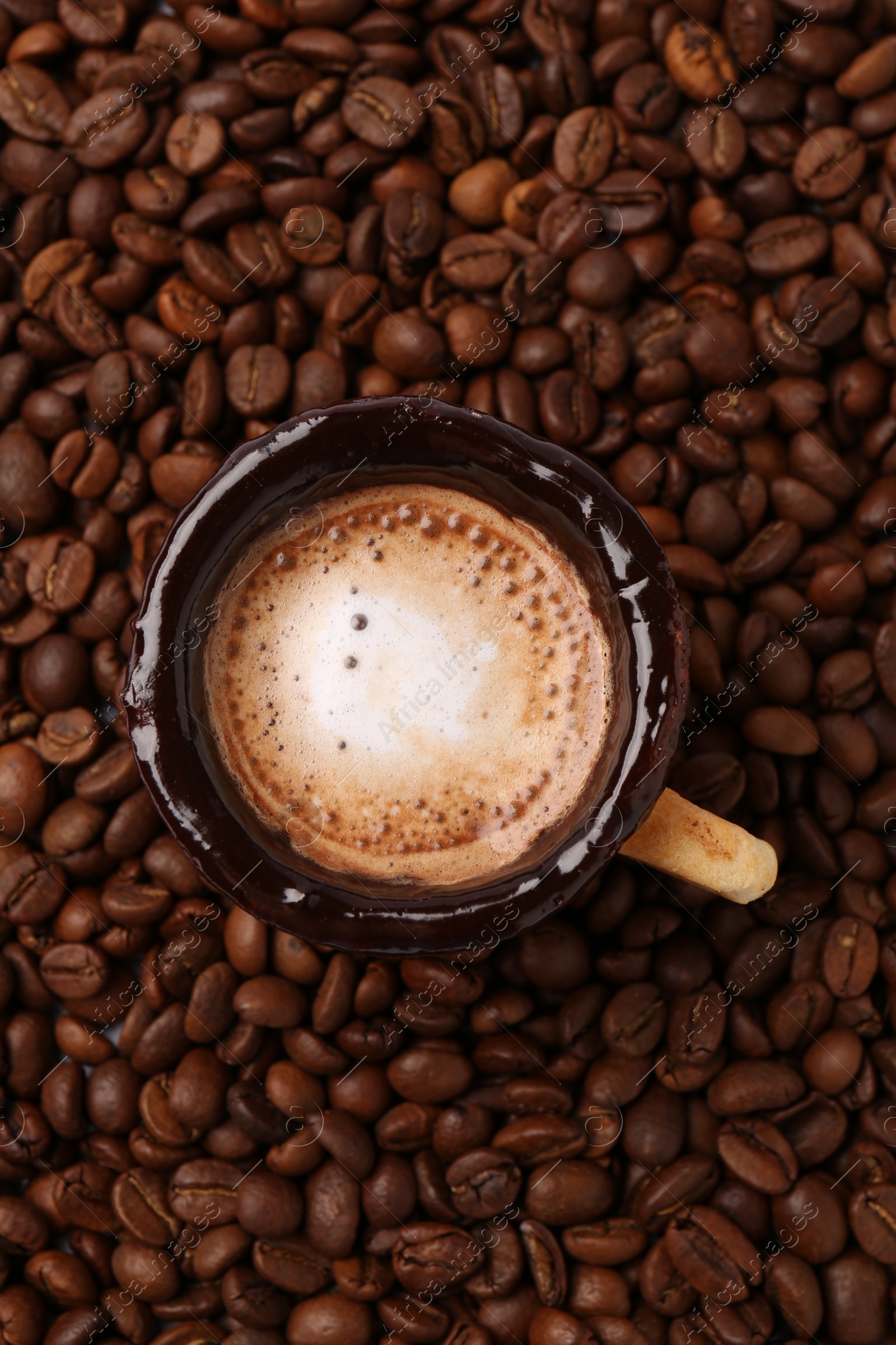 Photo of Delicious edible biscuit cup with espresso on roasted beans, top view