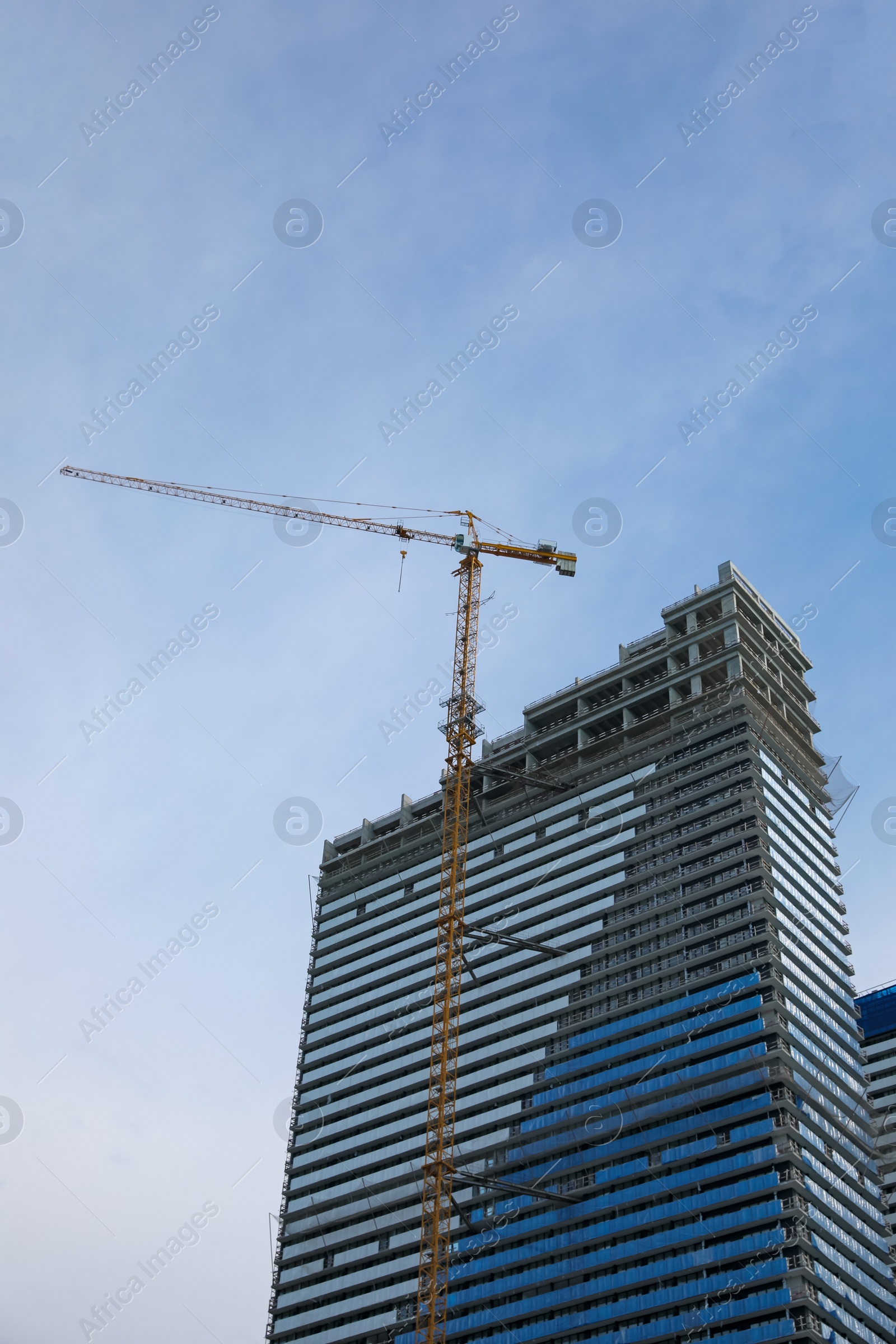 Photo of Construction site with tower crane near unfinished building, low angle view