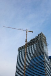 Construction site with tower crane near unfinished building, low angle view