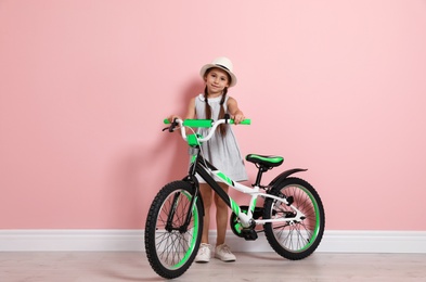 Photo of Portrait of cute little girl with bicycle near color wall