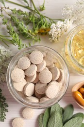 Photo of Different pills, flowers and herbs on white wooden table, flat lay. Dietary supplements