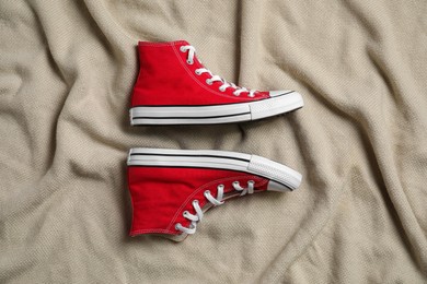 Pair of new stylish red sneakers on beige cloth, flat lay