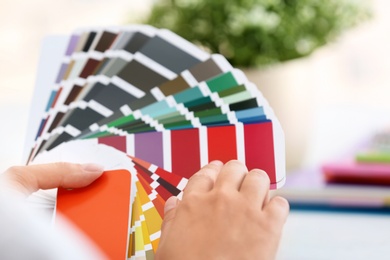 Photo of Woman with paint color palette samples on blurred background, closeup