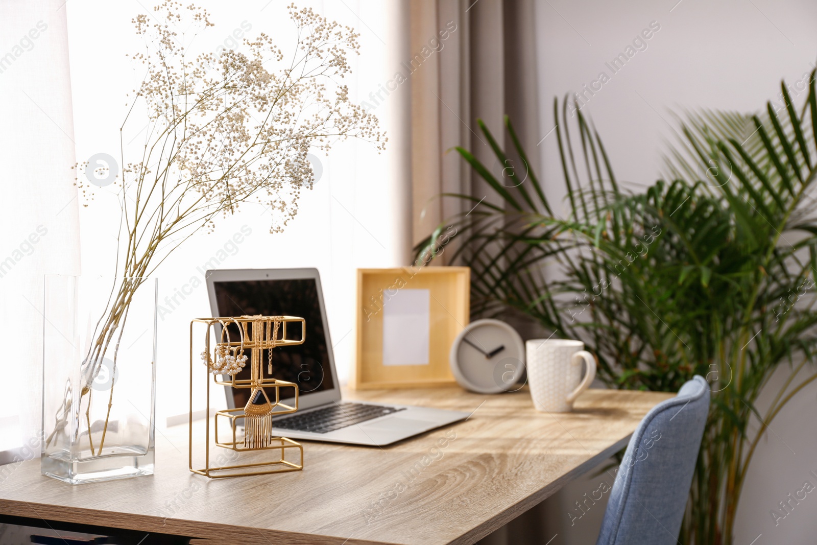 Photo of Stylish workplace interior with laptop on wooden table near window