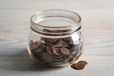 Photo of Glass jar with coins on white wooden table, closeup