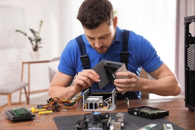 Male technician repairing power supply unit at table indoors