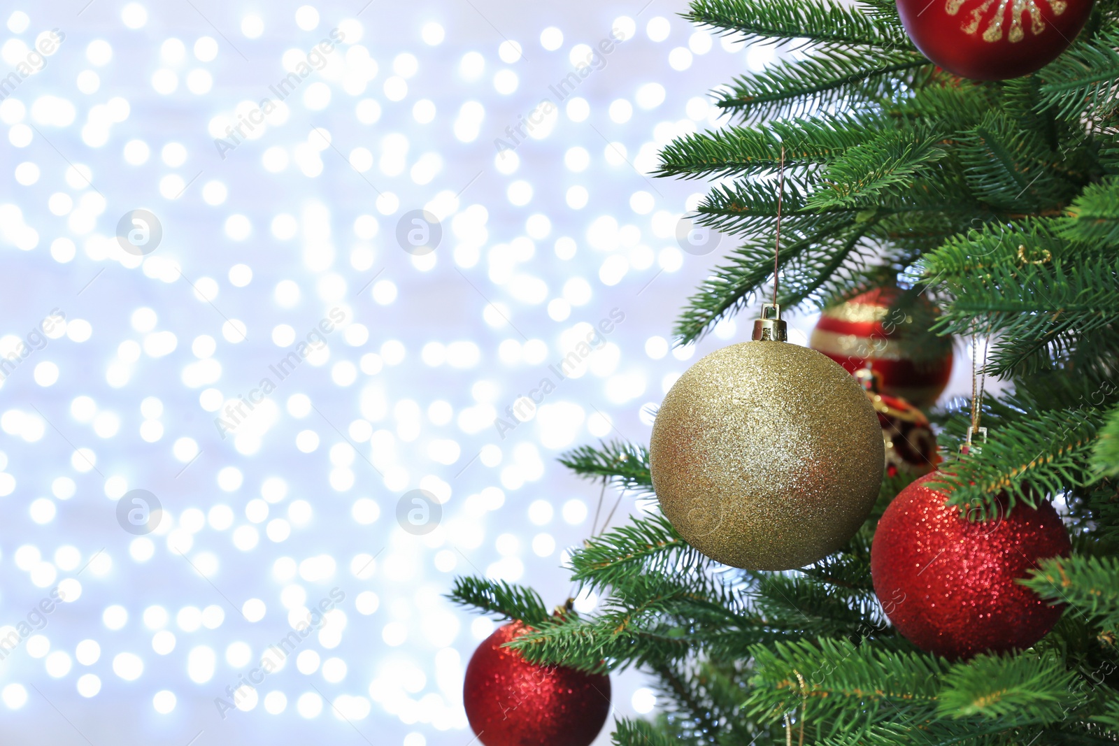 Photo of Christmas tree with festive decor against blurred fairy lights