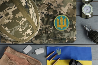 Photo of MYKOLAIV, UKRAINE - SEPTEMBER 26, 2020: Tactical gear, military uniform and Ukrainian flag on grey table, flat lay