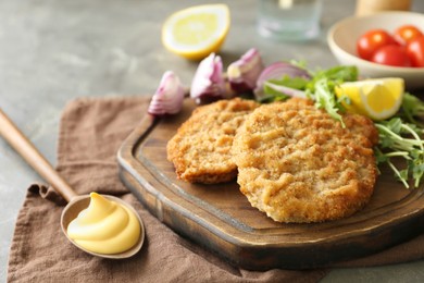 Photo of Tasty schnitzels served with sauce and fresh vegetables on table, closeup