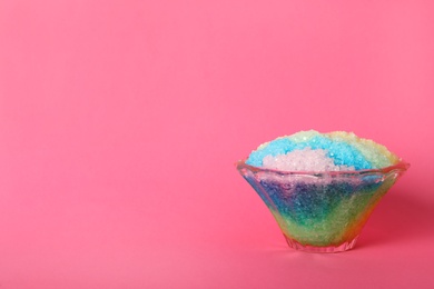 Rainbow shaving ice in glass dessert bowl on pink background, space for text