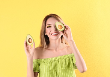 Portrait of young beautiful woman with ripe delicious avocado on color background