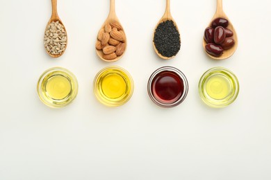 Vegetable fats. Different cooking oils in bowls and spoons with ingredients on white background, flat lay. Space for text