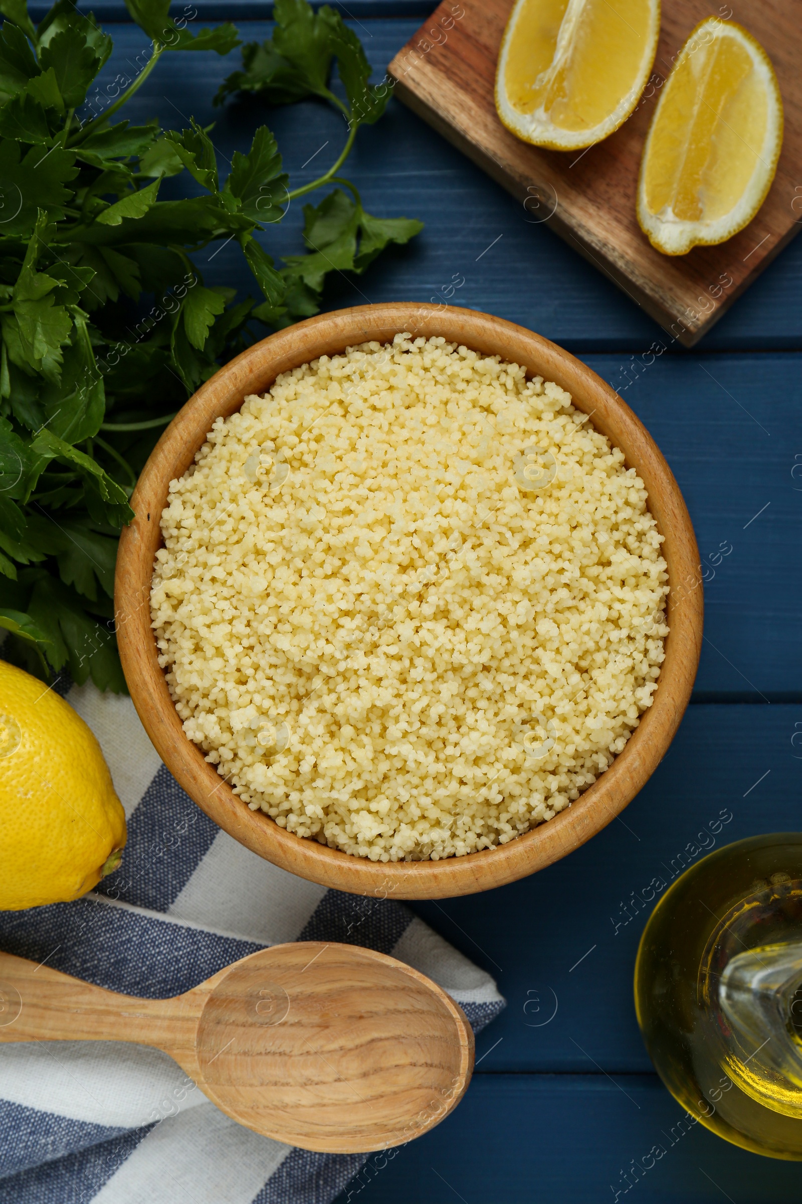 Photo of Tasty couscous and ingredients on blue wooden table, flat lay