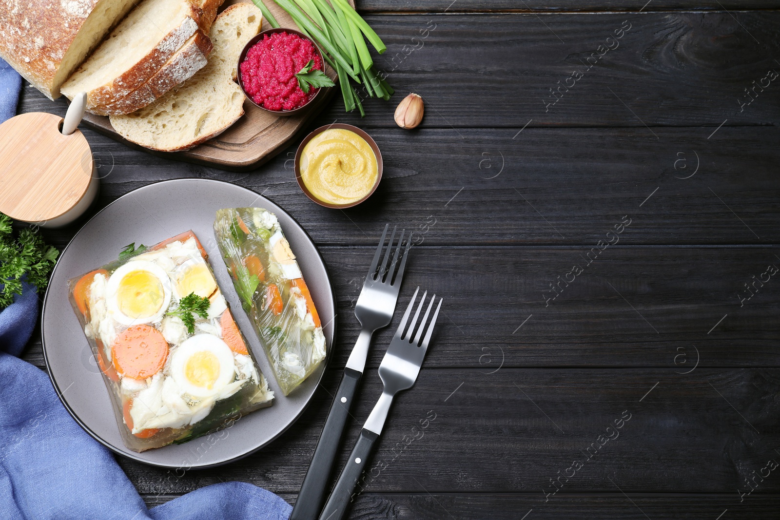 Photo of Delicious fish aspic served on black wooden table, flat lay. Space for text