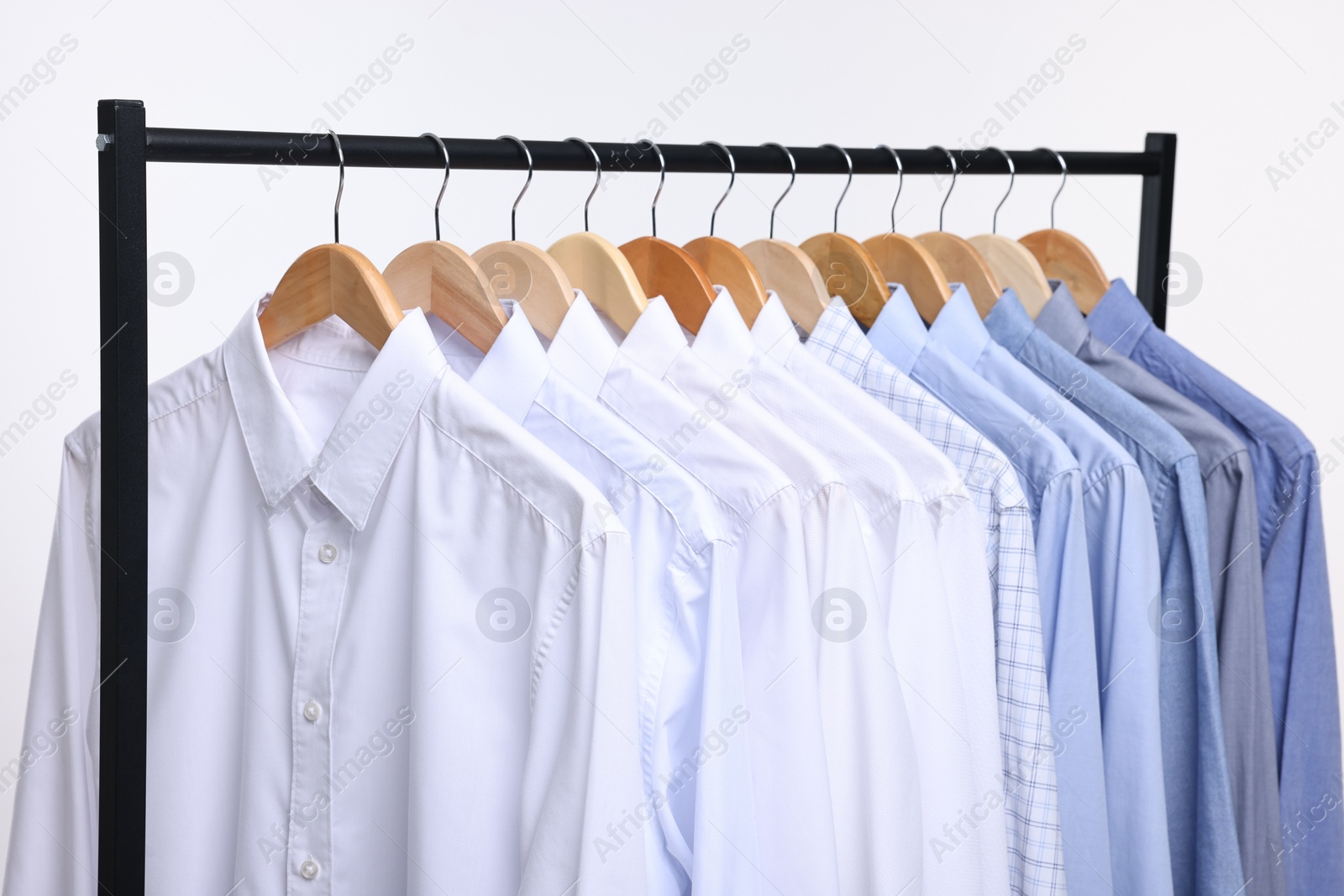 Photo of Dry-cleaning service. Many different clothes hanging on rack against white background, closeup