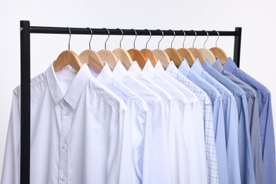 Dry-cleaning service. Many different clothes hanging on rack against white background, closeup