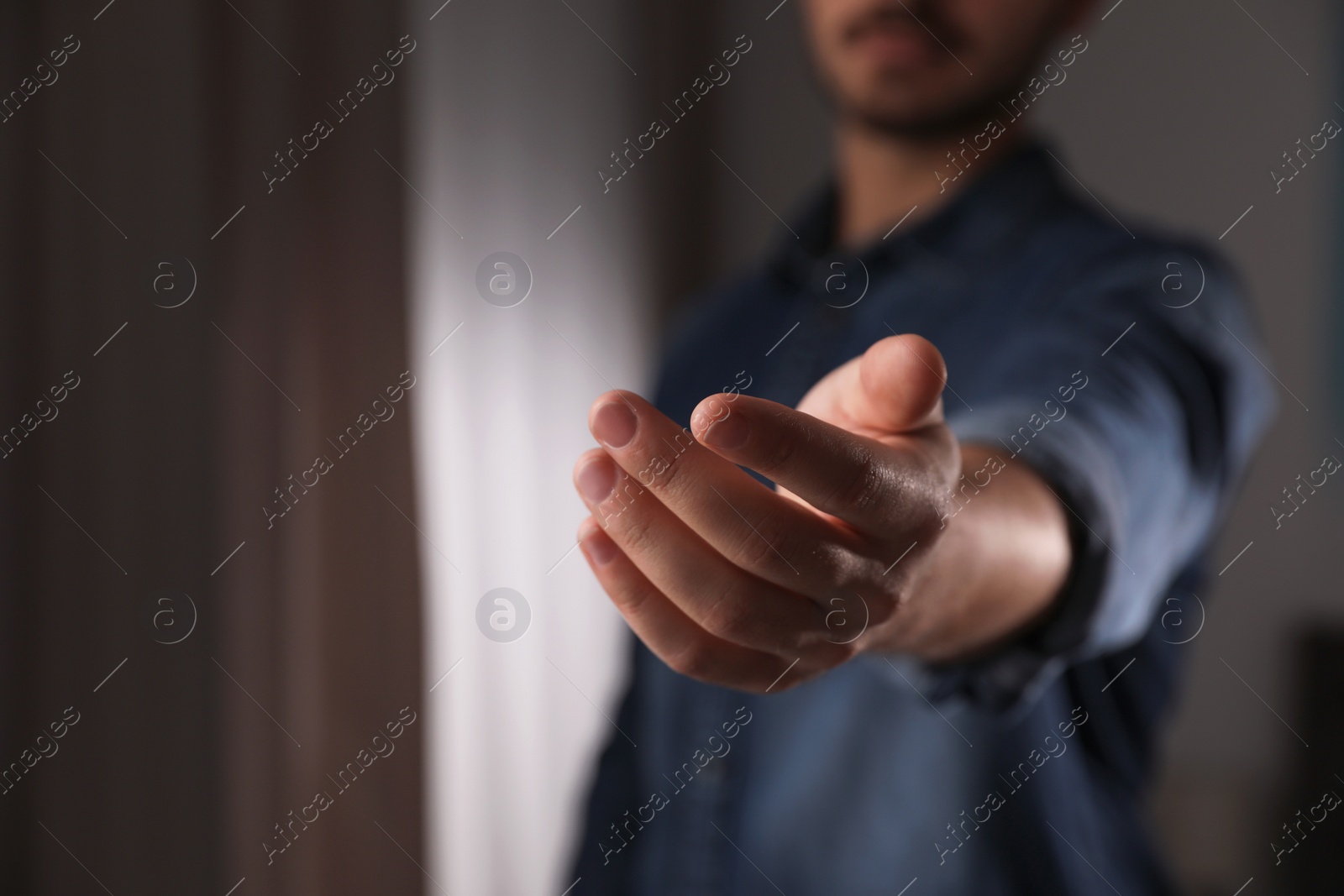 Photo of Man offering helping hand on blurred background, closeup. Space for text