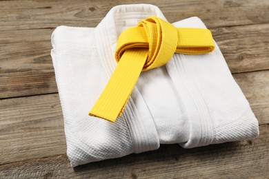 Photo of Yellow karate belt and white kimono on wooden background