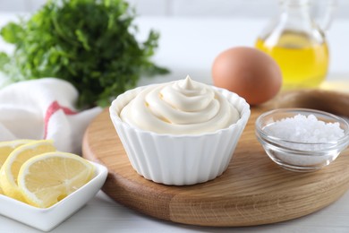 Photo of Fresh mayonnaise sauce in bowl and ingredients on table