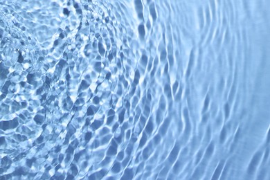 Image of Rippled surface of clear water on light blue background, closeup