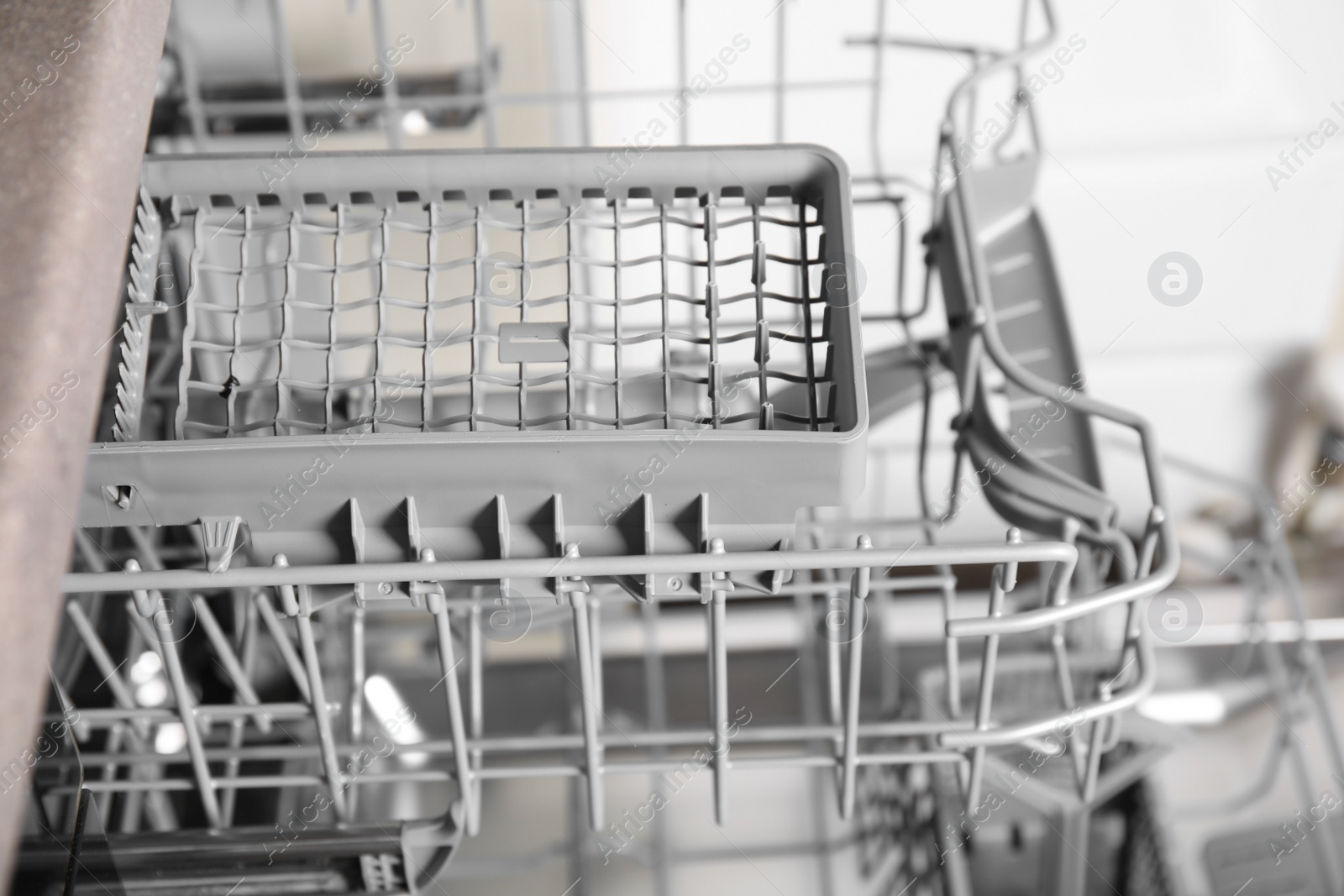 Photo of Open clean empty dishwasher in kitchen, closeup