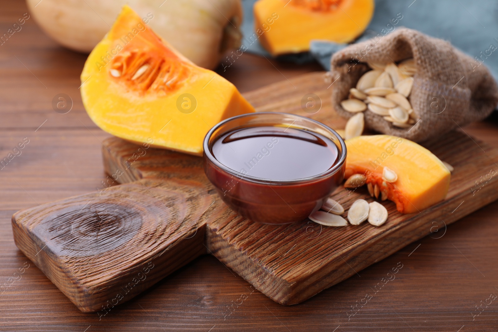 Photo of Glass bowl of pumpkin seed oil on wooden table