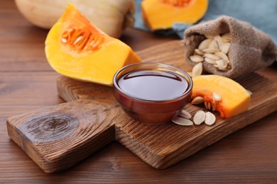 Photo of Glass bowl of pumpkin seed oil on wooden table