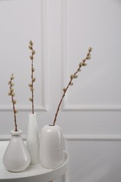 Beautiful pussy willow branches in vases on white table indoors