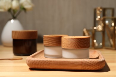 Photo of Jars of cream and tray on wooden table