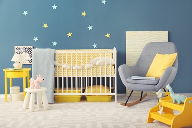 Photo of Baby room interior with crib and rocking chair near wall