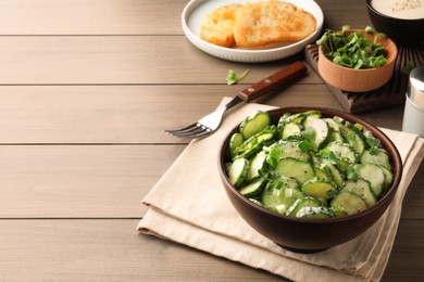 Delicious cucumber salad served on wooden table. Space for text