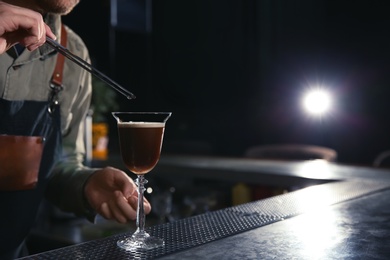 Barman adding coffee bean to martini espresso cocktail at counter, closeup. Space for text
