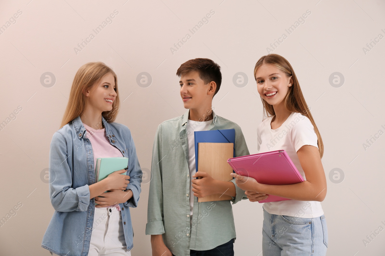 Photo of Group of teenage students with stationery on beige background