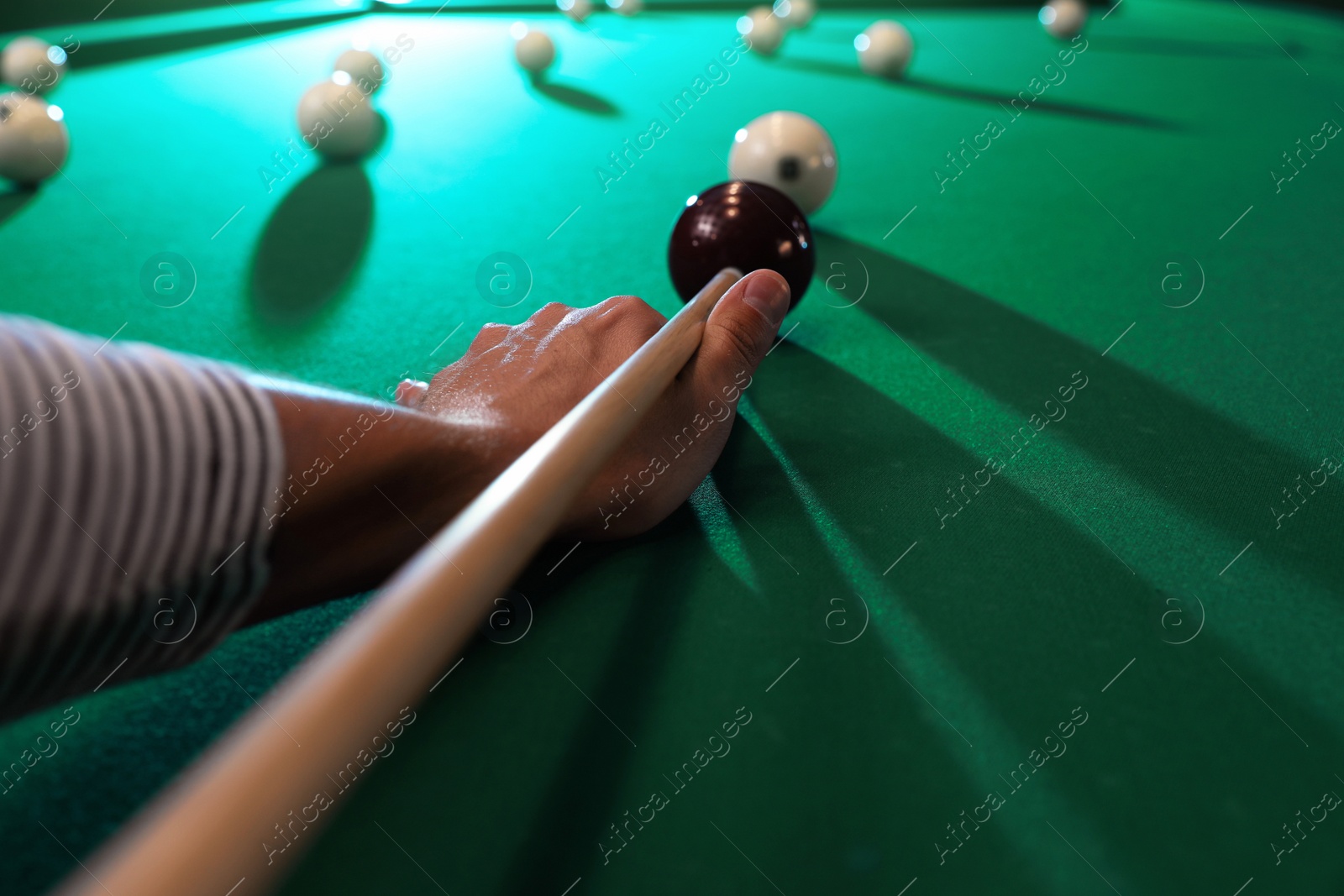 Photo of Young man playing Russian billiard indoors, closeup