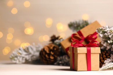 Gift boxes and Christmas decor on wooden table against blurred festive lights, space for text