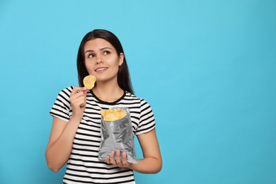 Photo of Beautiful woman eating potato chips on light blue background, space for text