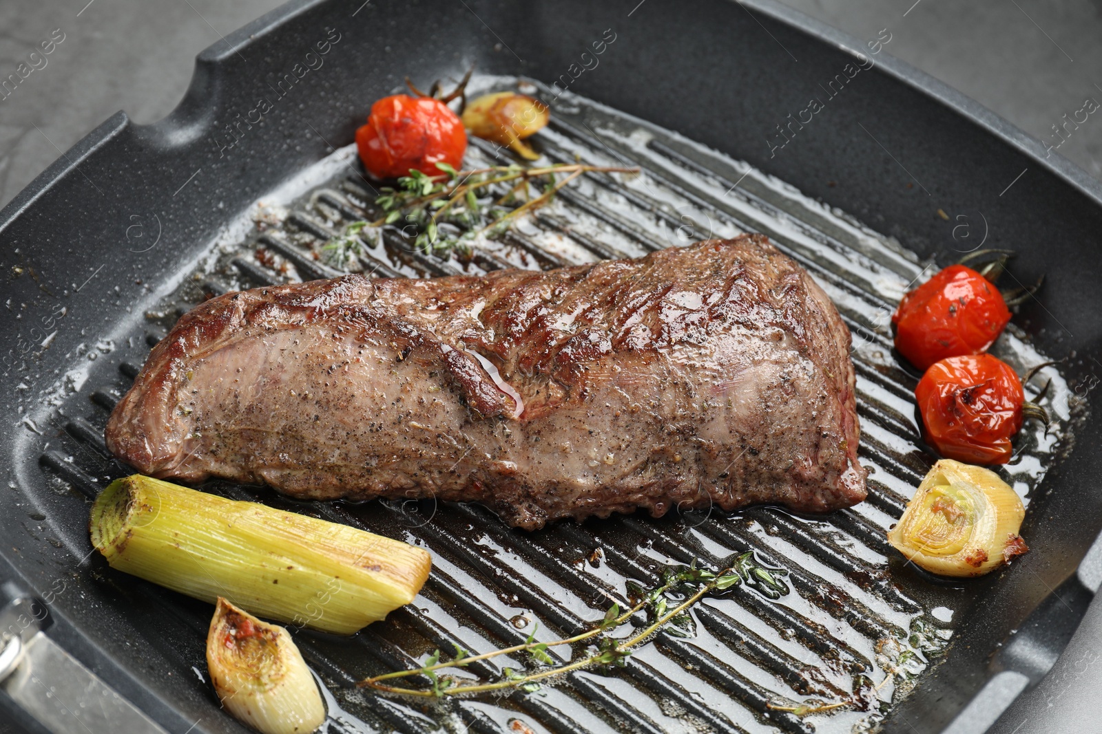 Photo of Delicious grilled beef meat and vegetables in pan on table, closeup