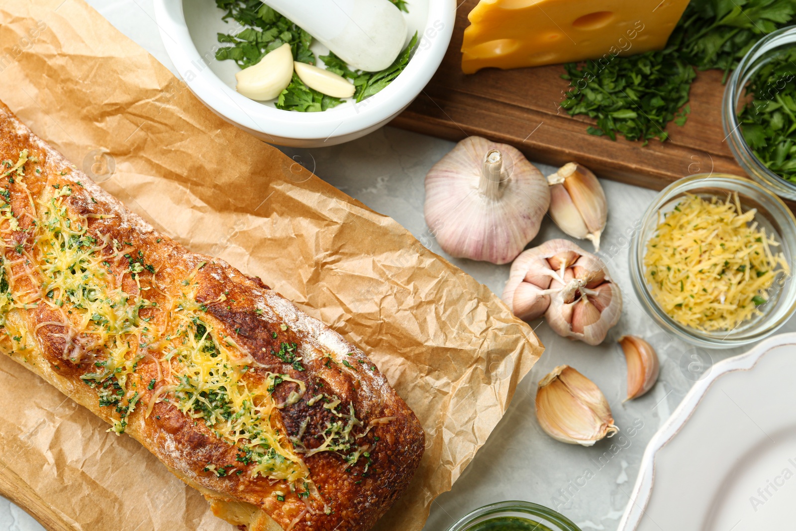 Photo of Tasty homemade garlic bread with cheese and herbs on grey table, flat lay