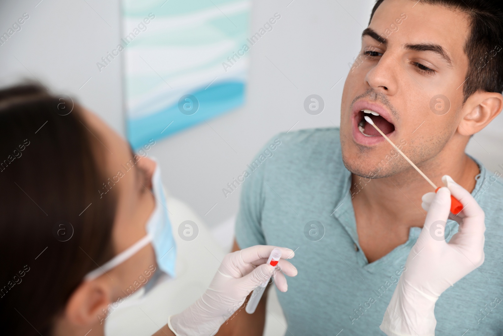 Photo of Doctor taking sample for DNA test from man in clinic