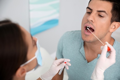 Photo of Doctor taking sample for DNA test from man in clinic