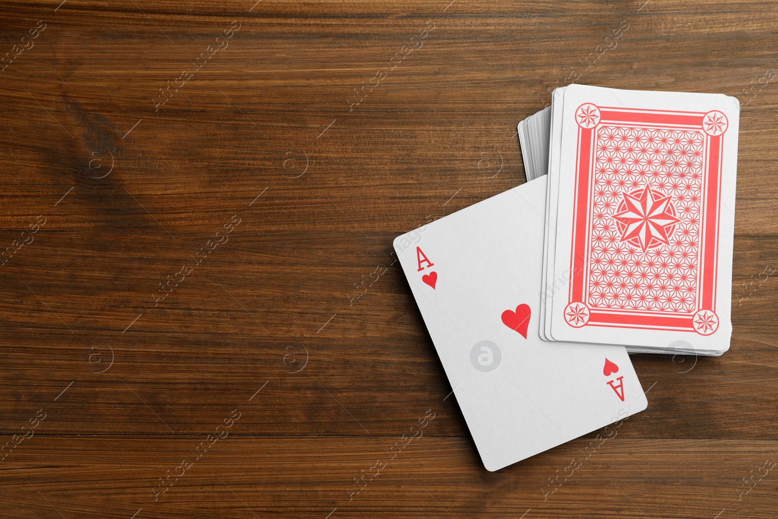 Photo of Deck of playing cards on wooden table, flat lay. Space for text